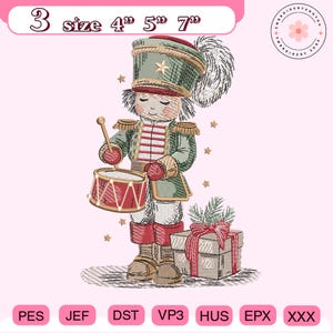 Könnte beinhalten: Gesticktes Design eines Spielzeugsoldaten, der eine Trommel spielt und eine grüne und rote Uniform und einen Hut trägt. Das Design enthält den Text "3 size 4" 5" 7"" oben und eine Geschenkbox mit roter Schleife. Das Design ist zum Sticken.