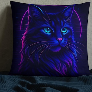 May include: Square throw pillow featuring a neon illustration of a black cat with blue eyes and pink accents. The cat is set against a dark background with a pink halo. The pillow is on a dark blue surface.