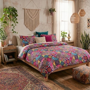 May include: A bed featuring a duvet cover and pillow shams with a vibrant, multi-coloured geometric patchwork pattern in shades of pink, blue, yellow, and green. The bedding set includes a solid magenta pillow and a textured cream-coloured pillow.