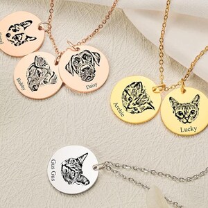 May include: Five gold and silver necklaces with round pendants featuring engraved images of pets. The pendants are labelled with the names "Bagel", "Bobby", "Daisy", "Archie", and "Lucky".
