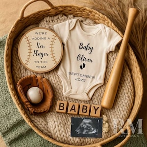 May include: A baby announcement with a baseball theme. The image features a cream-coloured onesie with the text "Baby Oliver" and "September 2025", a baseball bat, a baseball, a glove, and wooden blocks spelling "BABY". A sonogram is also included.