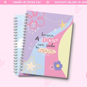 Puede incluir: Una libreta de espiral con una portada colorida que presenta un diseño abstracto en rosa, azul y amarillo. La portada tiene el texto "busca A DIOS con todo tu CORAZON" en español. La libreta es de tamaño A5, que es 21 cm por 14,8 cm.