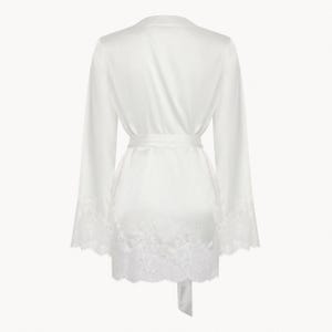 May include: A white satin robe with lace trim around the sleeves and hem. The robe has a tie belt and is a lightweight, comfortable garment.