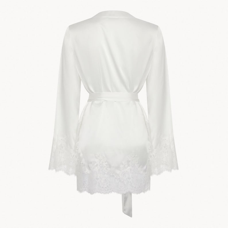 May include: A white satin robe with lace trim around the sleeves and hem. The robe has a tie belt and is a lightweight, comfortable garment.