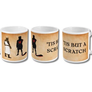 May include: White ceramic mug with a brown background featuring illustrations of knights and the phrase "'Tis but a scratch." The design includes a knight in white and black silhouettes of knights with swords.