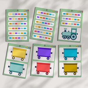 Peut inclure: Ensemble de cartes éducatives colorées. Les cartes présentent un train, des wagons et des rangées de blocs colorés. Les cartes sont sur un fond vert clair avec une bordure blanche. Le train et les wagons sont dans des tons de bleu, jaune, violet et rouge.