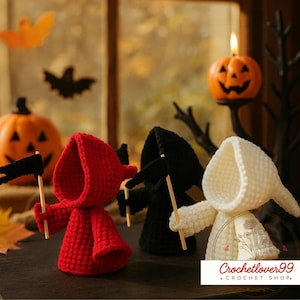 Könnte beinhalten: Drei gehäkelte Figuren in Rot, Schwarz und Weiß, jede mit einer kleinen schwarzen Flagge an einem Holzstab. Die Figuren sind mit Kapuzen versehen und stehen vor einem Halloween-Hintergrund mit Kürbissen und Fledermausdekorationen.