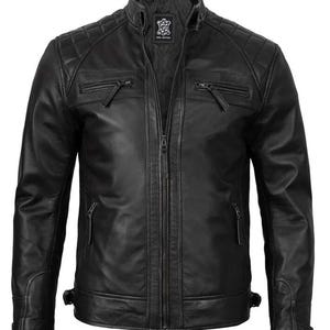 Könnte beinhalten: Schwarze Lederjacke mit Steppdesign an den Schultern, Stehkragen und mehreren Reißverschlusstaschen. Die Jacke hat einen durchgehenden Reißverschluss und verstellbare Taillenriemen. Die Jacke ist aus echtem Leder.