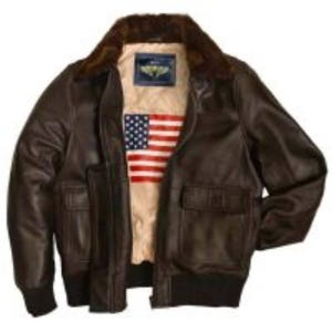 Puede incluir: Chaqueta bomber de cuero marrón con cuello de piel y puños de canalé negros. El interior de la chaqueta presenta un forro beige con un diseño de bandera americana y un parche. Se ven dos bolsillos delanteros.