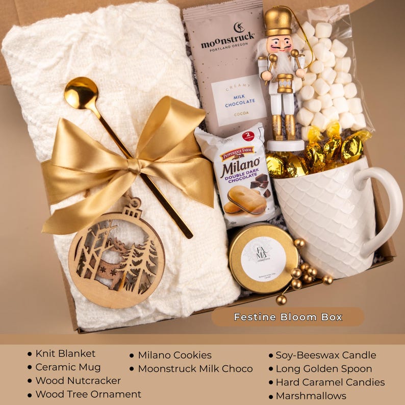 Golden holiday gift box with knit blanket, candle, ceramic mug, nutcracker, ornament, and cocoa — luxury Christmas care package for women or cozy winter gift.