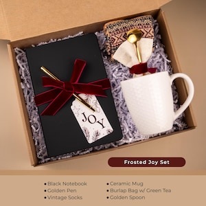 Joy holiday gift box with white mug, cozy patterned socks, gold spoon, black notebook, pen, and red ribbon — simple Christmas gift for coworker, teacher, or friend.
