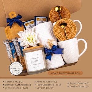 Peut inclure: Coffret cadeau Home Sweet Home avec planche &agrave; d&eacute;couper en bambou, serviette blanche, bougie de soja, tasses en c&eacute;ramique, biscuits aux amandes, th&eacute;, dessous de verre en rotin et cuill&egrave;res dor&eacute;es. Carte de v&oelig;ux personnalis&eacute;e incluse.