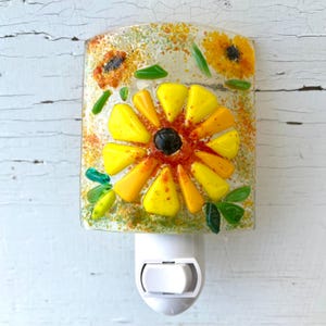 May include: A yellow and orange stained glass flower nightlight with a white plug-in base.