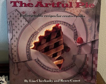 Puede incluir: Un libro de cocina titulado "The Artful Pie" con una porción de tarta en la portada. La portada presenta una porción de tarta con una corteza de rejilla, frambuesas y el texto "Unforgettable recipes for creative cooks" y los nombres de los autores.