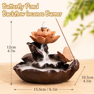 May include: A brown ceramic Butterfly Pond backflow incense burner featuring a lotus flower, a butterfly, and a leaf-shaped base. The burner measures 12 cm in height, 10.5 cm in depth, and 15.5 cm in width, with white smoke flowing downwards.