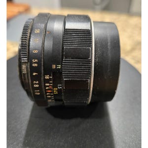 以下が含まれることがあります： 黒いカメラレンズ。 1.8から16までの絞り設定と、溝付きフォーカスリングを備えています。 レンズにはメートル単位の距離マークも付いており、最短焦点距離は0.45メートルです。 レンズにはAUTO設定があります。