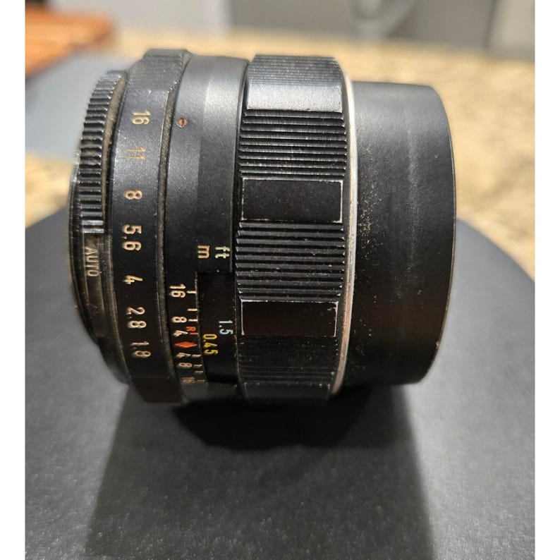 以下が含まれることがあります： 黒いカメラレンズ。 1.8から16までの絞り設定と、溝付きフォーカスリングを備えています。 レンズにはメートル単位の距離マークも付いており、最短焦点距離は0.45メートルです。 レンズにはAUTO設定があります。
