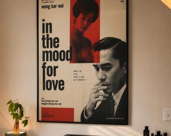 Puede incluir: Un póster de película enmarcado de In the Mood for Love de Wong Kar Wai, con un retrato en tonos rojos de una mujer y un retrato en blanco y negro de un hombre fumando. El póster incluye el título, los nombres del reparto y texto en francés.