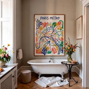 Könnte beinhalten: Ein gerahmter Wandkunstdruck mit dem Titel PARIS METRO, der eine bunte, abstrakte Karte des Pariser U-Bahn-Systems mit blauen, gelben, grünen und roten Formen zeigt, platziert über einer weißen Badewanne mit Klauenfüßen in einem Raum mit hellgrauen Wänden.