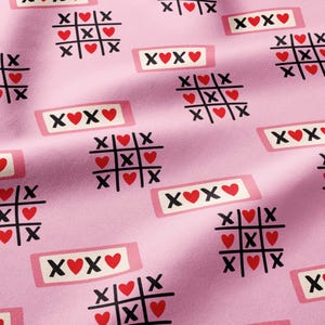 May include: A light pink fabric featuring a repeating pattern of black tic-tac-toe grids with red heart symbols in place of O's, interspersed with rectangular white labels containing the black text XOXO with a red heart in the center.