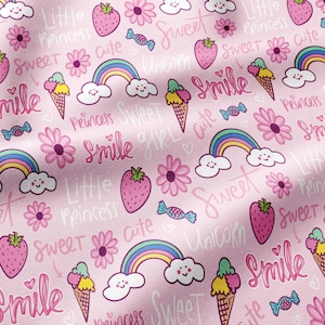 May include: A light pink fabric featuring a repeating pattern of strawberries, rainbows with clouds, ice cream cones, flowers, and candies. The design includes handwritten-style text with words such as Little Princess, Sweet, Cute, Smile, and Unicorn.
