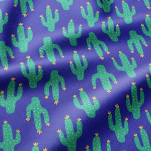 May include: A fabric pattern featuring a repeating print of light green saguaro cacti with small yellow flowers on their tops, set against a solid deep purple background. The cacti are arranged in a scattered, non-uniform orientation across the surface.