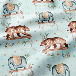 May include: A light blue fabric featuring a repeating pattern of brown bears and gray elephants. Each animal is depicted standing on a wooden branch with hanging decorative elements including leaves, suns, and rainbows, interspersed with small dots.