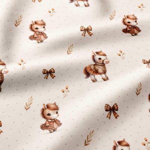 May include: A light beige fabric featuring a repeating pattern of cartoon ponies wearing brown coats, interspersed with small brown plaid bows and delicate sprigs of leaves, all set against a background of tiny, evenly spaced brown dots.
