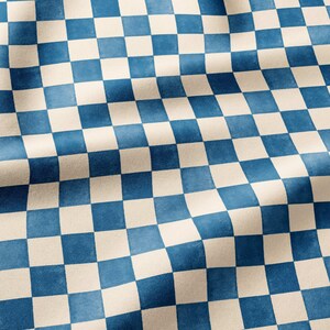 May include: A fabric featuring a repeating checkerboard pattern in alternating shades of deep blue and off-white. The material displays soft folds and ripples, creating a textured appearance across the surface of the textile design.