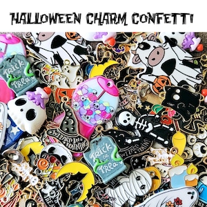 May include: A collection of Halloween-themed charm confetti. The charms feature various designs, including ghosts, bats, tombstones, and a skeleton. The text "HALLOWEEN CHARM CONFETTI" is at the top of the image. The charms are in various colors, including black, white, orange, and green.