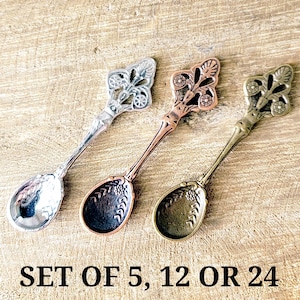 May include: Three decorative spoons with ornate floral designs. The spoons are in silver, copper, and bronze tones. The text "SET OF 5, 12 OR 24" is at the bottom of the image.