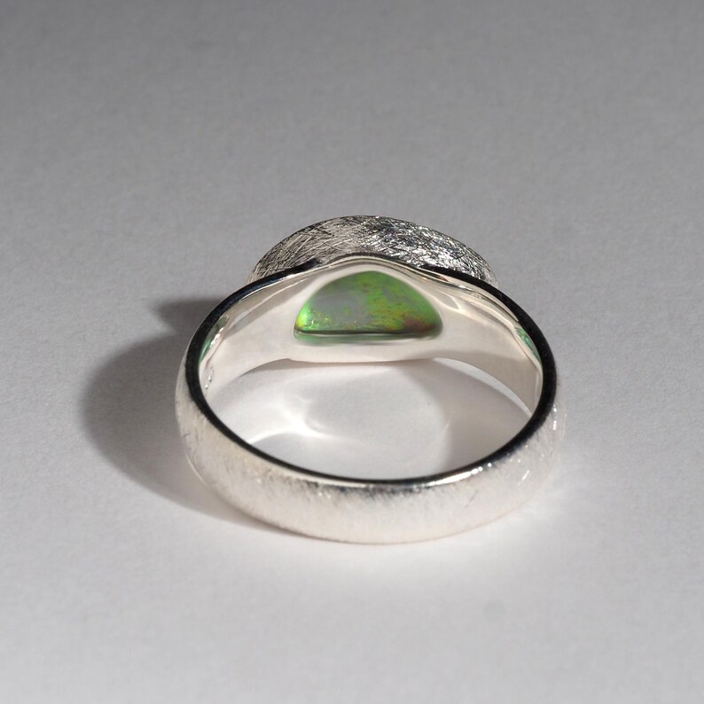May include: A silver ring with a textured band and a green opal gemstone set in the center.