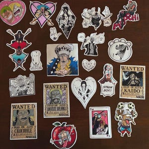 May include: A collection of various One Piece anime stickers featuring characters like Luffy, Zoro, Law, and Kaido. The set includes rectangular wanted posters, heart-shaped designs, and individual character illustrations in black, white, and color.
