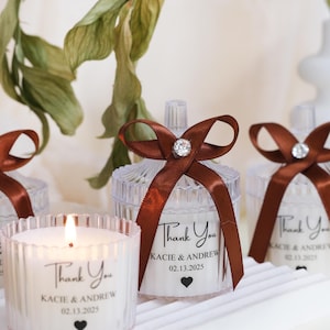 May include: Clear glass candle jars with brown ribbon bows and personalized labels that say "Thank You Kacie & Andrew 02.13.2025".