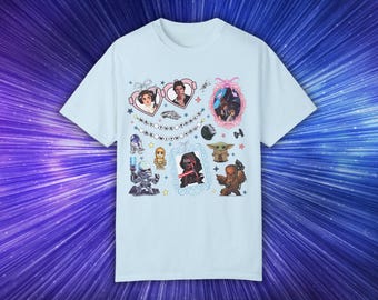 May include: Light blue t-shirt with a graphic print of various Star Wars characters, including Princess Leia, Han Solo, Darth Vader, Yoda, and Chewbacca. The text "May the Force be with you" is printed on the shirt.
