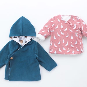 Könnte beinhalten: Zwei Babyjacken. Eine ist teal mit Kapuze und Knopfverschluss. Die Kapuze und das Futter haben ein gemustertes Design. Die andere Jacke ist rosa mit einem weißen Gänsemuster und weißem Besatz.