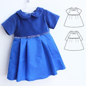 May include: A blue dress with a round collar and short sleeves hangs on a hanger. The bodice is a darker blue velvet, and the skirt is a pleated, lighter blue fabric. A decorative band with sequins accents the waist. Two dress pattern illustrations are to the right.