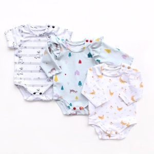 May include: Three baby bodysuits with different patterns. One has a musical note design, another has a light blue background with trees and deer, and the third has a white background with yellow chickens.