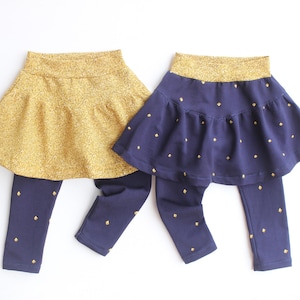 May include: Two sets of children's leggings with attached skirts. One set is gold glitter, the other is navy blue with gold diamond accents. Both sets have a gold glitter waistband.