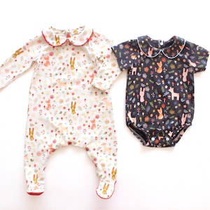 May include: Two baby rompers. One is white with a red-trimmed collar and a pattern of bunnies, foxes, and flowers. The other is navy blue with a white-trimmed collar and a similar pattern. Both have short sleeves and a button closure.
