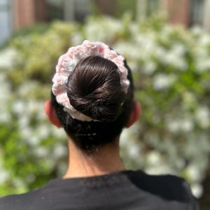 A pink and white crocheted hair scrunchie