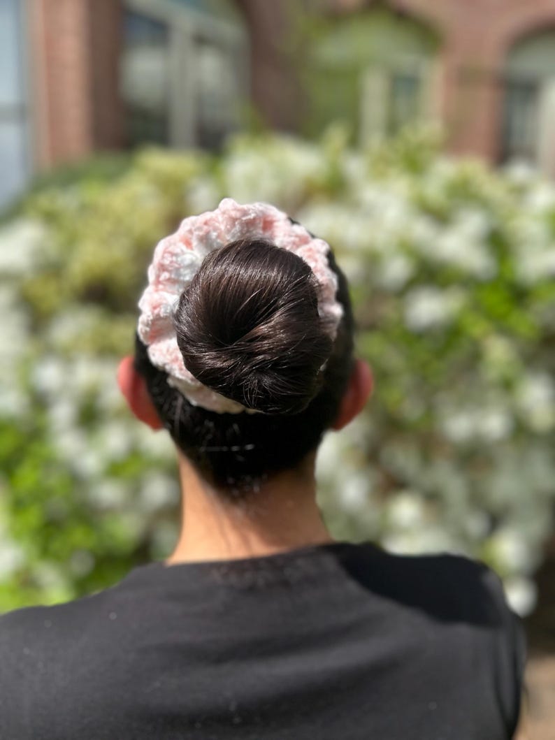 A pink and white crocheted hair scrunchie