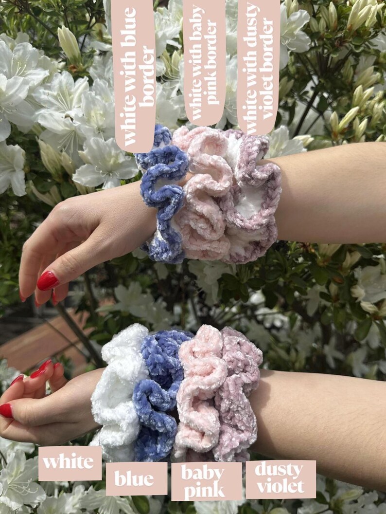 Four scrunchies in different colors. The scrunchies are made of a soft, fluffy material. The colors are white, blue, baby pink, and dusty violet. The scrunchies are stacked on top of each other. The scrunchies are labeled with the words 'white', 'blue', 'baby pink', and 'dusty violet'.