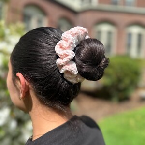 A pink and white velvet crochet scrunchie with a fluffy texture.