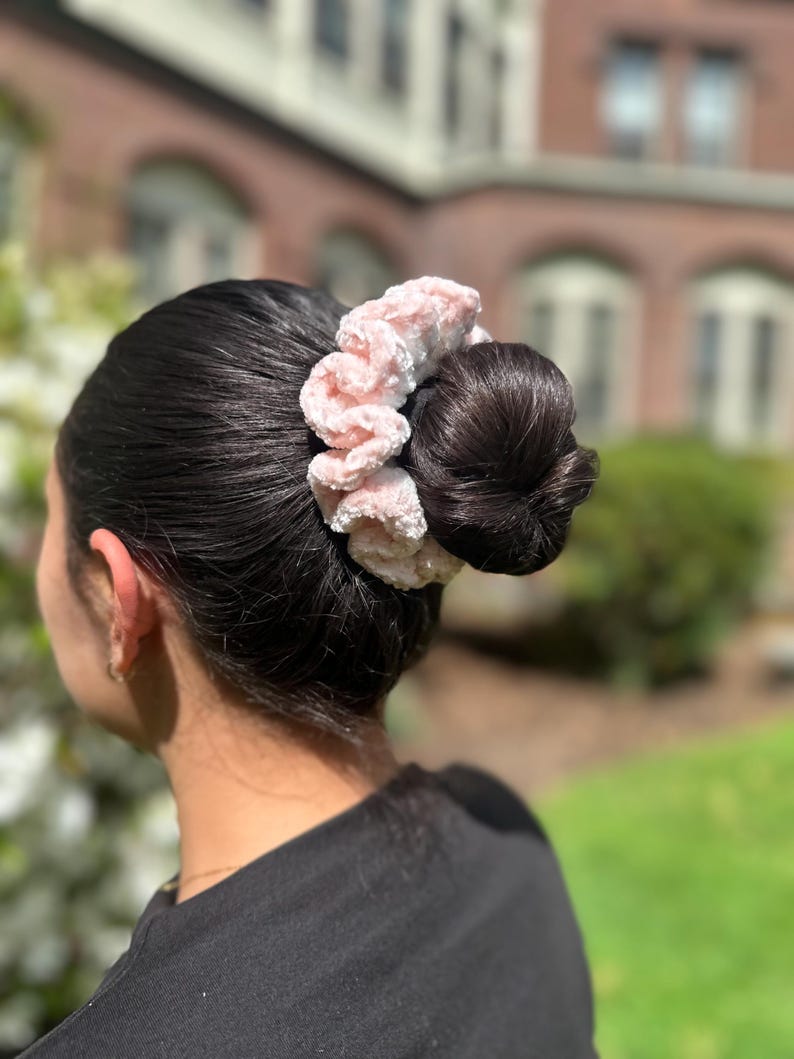 A pink and white velvet crochet scrunchie with a fluffy texture.