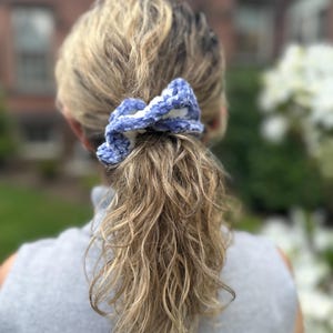 A blue and white crocheted hair scrunchie.