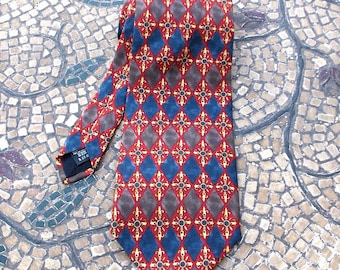 May include: A red, blue, and gold patterned tie with a diamond pattern. The tie is on a mosaic tile background.