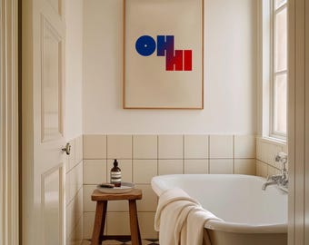 May include: A white bathtub with a white towel on the side, a wooden stool with a bottle of soap and a white ceramic tile wall. A framed print with the word "OH HI" in blue and red letters hangs on the wall.