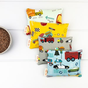 May include: Five colorful fabric pouches with a variety of vehicle designs, including cars, trucks, and a scooter. The pouches have a light blue, yellow, gray, and green background. The text "Little Stitches" is on the bottom of each pouch.