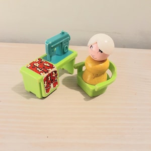 Peut inclure: Un ensemble de jouets en plastique comprenant une table à coudre vert citron avec une machine à coudre sarcelle et un accent en tissu floral rouge. À côté de la table se trouve une chaise vert citron avec une figurine en bois jaune et blanc.